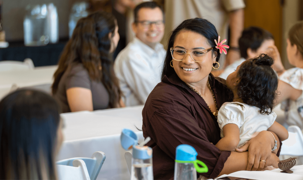 a Samoan woman holding her baby talking to another woma